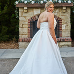 Strapless satin plus size wedding gown with pleated bodice and detachable belt included. A-line skirt with box pleats, pockets and long train. Michelle Bridal style MB2523 is available in ivory or black.