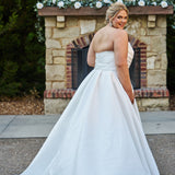 Strapless satin plus size wedding gown with pleated bodice and detachable belt included. A-line skirt with box pleats, pockets and long train. Michelle Bridal style MB2523 is available in ivory or black.