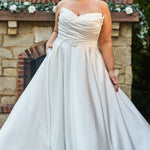 Strapless satin plus size wedding gown with pleated bodice and detachable belt included. A-line skirt with box pleats, pockets and long train. Michelle Bridal style MB2523 is available in ivory or black.