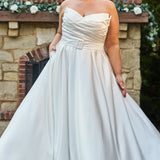 Strapless satin plus size wedding gown with pleated bodice and detachable belt included. A-line skirt with box pleats, pockets and long train. Michelle Bridal style MB2523 is available in ivory or black.