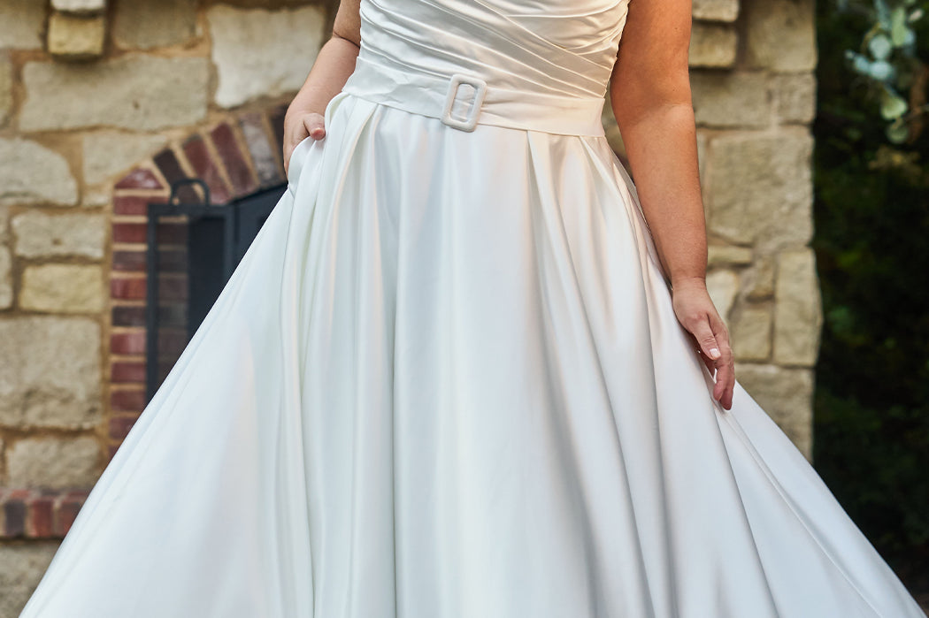 Strapless satin plus size wedding gown with pleated bodice and detachable belt included. A-line skirt with box pleats, pockets and long train. Michelle Bridal style MB2523 is available in ivory or black.