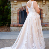 Plus size A-line oversized floral weding dress in ivory or champagne. Style MB2525 from Michelle Bridal by Sydney's Closet has illusions straps covered in appliques, natural waisltine, long flowy A-line skirt and long train with covered buttons.