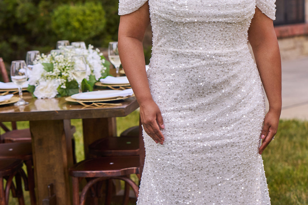 Sexy curvy plus-size fitted formal bridal dress with drape sleeves, exposed boning and ruching.  Beaded bling fabric with sequins, stones and pearls.  Long train and ruching on the buttocks. MB2528 from Michelle Bridal by Sydney's Closet.
