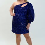 This is SC8133 in our Sydney's Closet Homecoming collection. This plus size party dress comes in black, blue, purple, and red! This dress has a one shoulder long sleeve pouf sleeve, a cutout bodice, and a natural waistline. This fitted all over sequin dress has the spotlight as the most perfect dress for this homecoming season!
