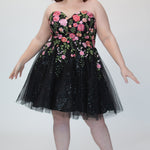 SC8137 Front view. Black sparkle tulle short a-line party dress with pink floral embroidered roses. Strapless sweetheart neckline, long invisible center back zipper.  Available only in black floral. Curvy sizes 10-32. Model in picture is 5 foot 9 inches and a size 16.