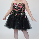 SC8137 Front view. Black sparkle tulle short a-line party dress with pink floral embroidered roses. Strapless sweetheart neckline, long invisible center back zipper.  Available only in black floral. Curvy sizes 10-32. Model in picture is 5 foot 9 inches and a size 16.