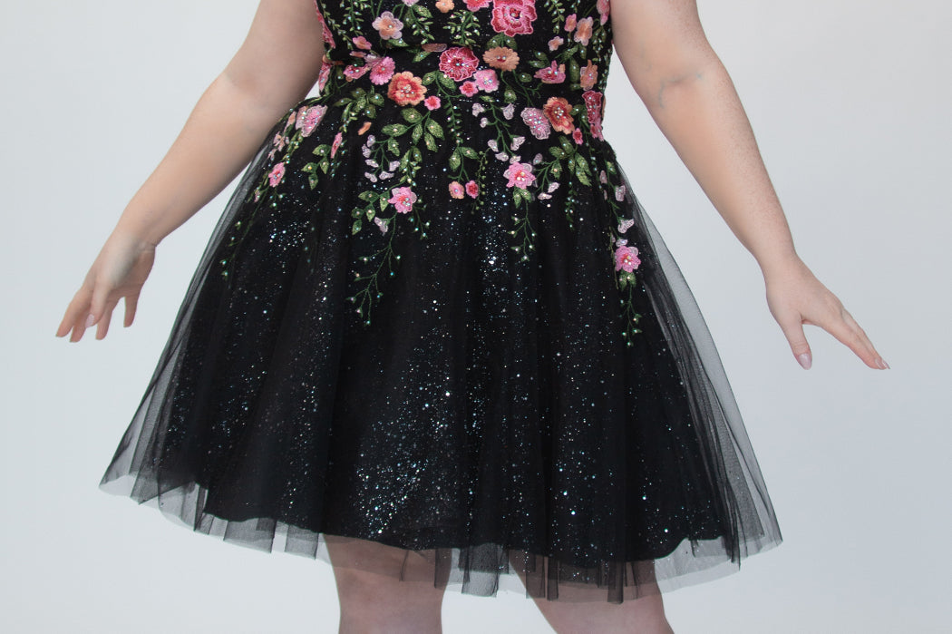 SC8137 Front view. Black sparkle tulle short a-line party dress with pink floral embroidered roses. Strapless sweetheart neckline, long invisible center back zipper.  Available only in black floral. Curvy sizes 10-32. Model in picture is 5 foot 9 inches and a size 16.
