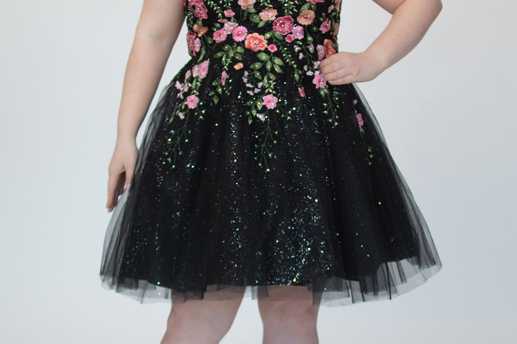 SC8137 Front view. Black sparkle tulle short a-line party dress with pink floral embroidered roses. Strapless sweetheart neckline, long invisible center back zipper.  Available only in black floral. Curvy sizes 10-32. Model in picture is 5 foot 9 inches and a size 16.