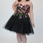 SC8137 Front view. Black sparkle tulle short a-line party dress with pink floral embroidered roses. Strapless sweetheart neckline, long invisible center back zipper.  Available only in black floral. Curvy sizes 10-32. Model in picture is 5 foot 9 inches and a size 16.
