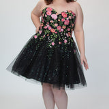 SC8137 Front view. Black sparkle tulle short a-line party dress with pink floral embroidered roses. Strapless sweetheart neckline, long invisible center back zipper.  Available only in black floral. Curvy sizes 10-32. Model in picture is 5 foot 9 inches and a size 16.