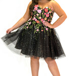SC8137 Front view. Black sparkle tulle short a-line party dress with pink floral embroidered roses. Strapless sweetheart neckline, long invisible center back zipper.  Available only in black floral. Curvy sizes 10-32. Model in picture is 5 foot 9 inches and a size 16.