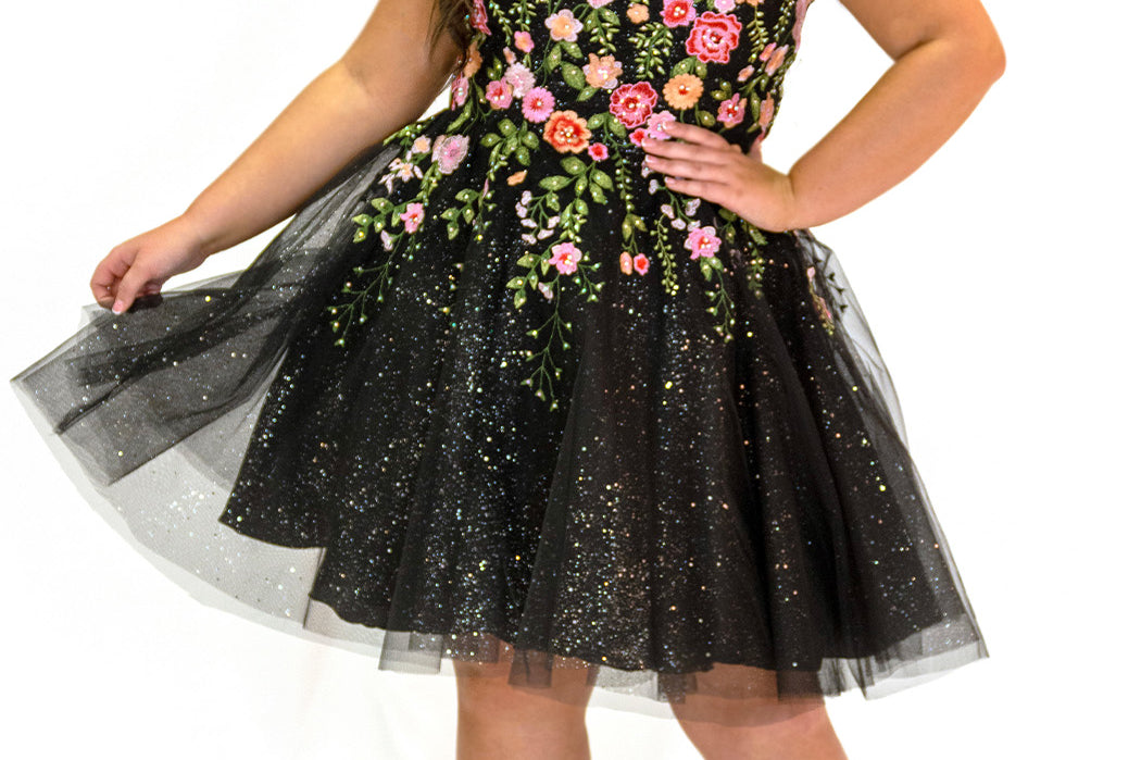SC8137 Front view. Black sparkle tulle short a-line party dress with pink floral embroidered roses. Strapless sweetheart neckline, long invisible center back zipper.  Available only in black floral. Curvy sizes 10-32. Model in picture is 5 foot 9 inches and a size 16.