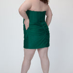 Short fitted green party dress SC8143 by Sydney's Closet. Back view.  Strapless, exposed boning basque waist and ruched fitted skirt in shimmer stretch knit. Availability in black, purple, red, ivory, green and royal. Model in picture is 5'9.