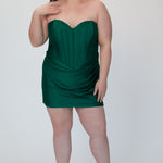 Short fitted green party dress SC8143 by Sydney's Closet. Front view.  Strapless, exposed boning basque waist and ruched fitted skirt in shimmer stretch knit. Long invisible center back zipper. Availability in black, purple, red, ivory, green and royal. Model in picture is 5'9.
