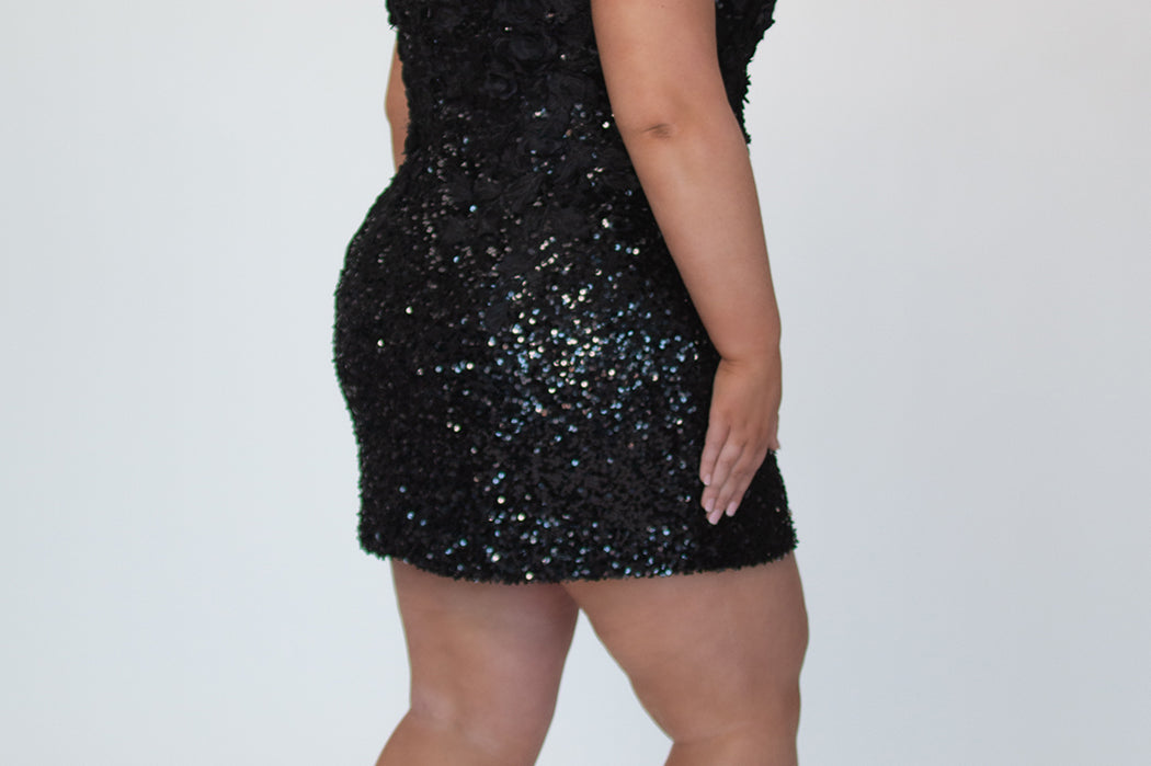 Short fitted Onyx black party dress SC8145 by Sydney's Closet. Back view.  Fully sequined short gown, with 3D floral embellishments on bodice. Thick bra-friendly straps, deep v-neckline. Long invisible center back zipper. Availability in lilac purple, onyx black and ruby red . Model in picture is 5'9.