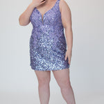 Short fitted Lilac party dress SC8145 by Sydney's Closet. Front view.  Fully sequined short gown, with 3D floral embellishments on bodice. Thick bra-friendly straps, deep v-neckline. Long invisible center back zipper. Availability in lilac purple, onyx black and ruby red . Model in picture is 5'9.
