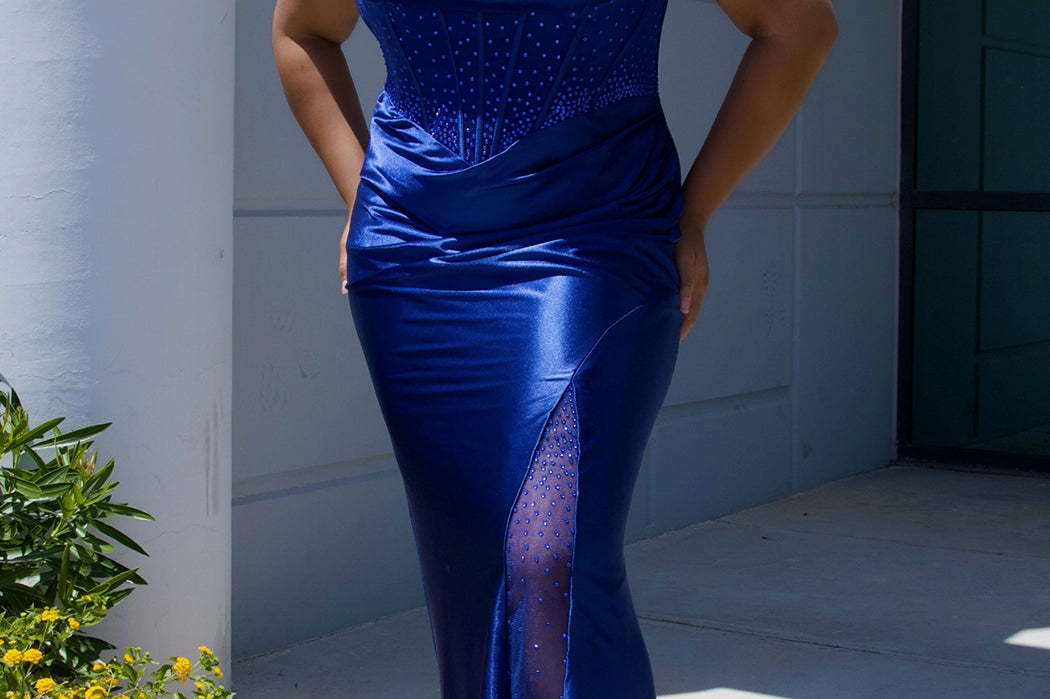 Sexy plus size fitted prom dress with double spaghetti straps, pleated bodice with optional bodice lining.  Exposed boning with hot fix stones on basque waistline.  Slim fitted skirt with ruching. High slit filled in with mesh and hot fix stones. Tease Prom style TE2516 avialable in berry, forest and navy.