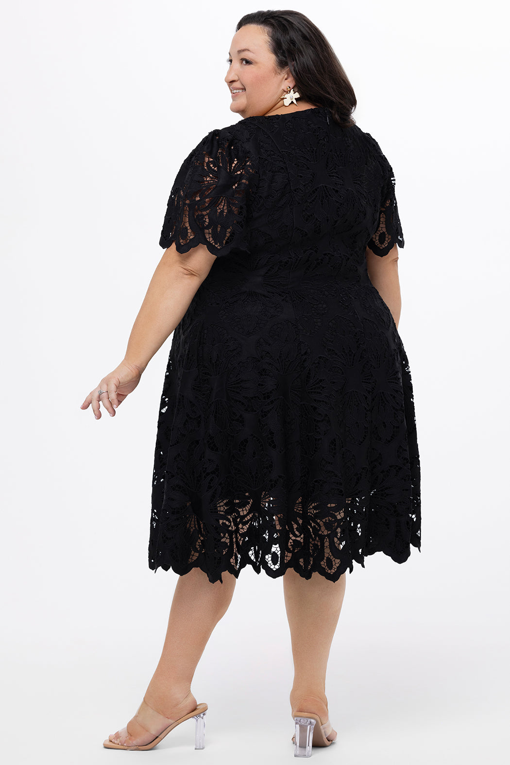 Plus size little black dress made of Guipure lace. Short sleeves, scoop neckline and center back zipper. CE2601 available in sizes 14-24 in black. Celebrations by Sydney's Closet.