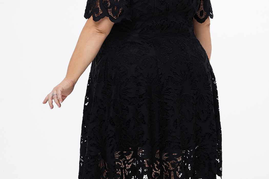 Plus size little black dress made of Guipure lace. Cap sleeves, scoop neckline and center back zipper. CE2601 available in sizes 14-24 in black. Celebrations by Sydney's Closet.