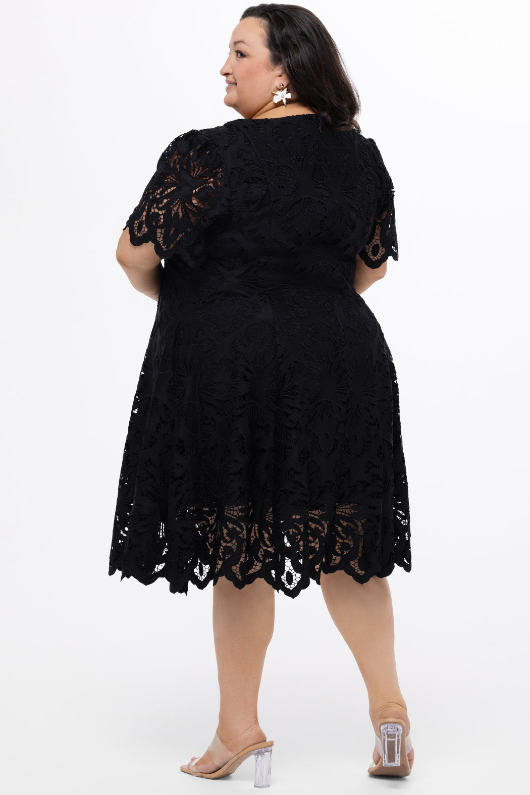 Plus size little black dress made of Guipure lace. Short sleeves, scoop neckline and center back zipper. CE2601 available in sizes 14-24 in black. Celebrations by Sydney's Closet.