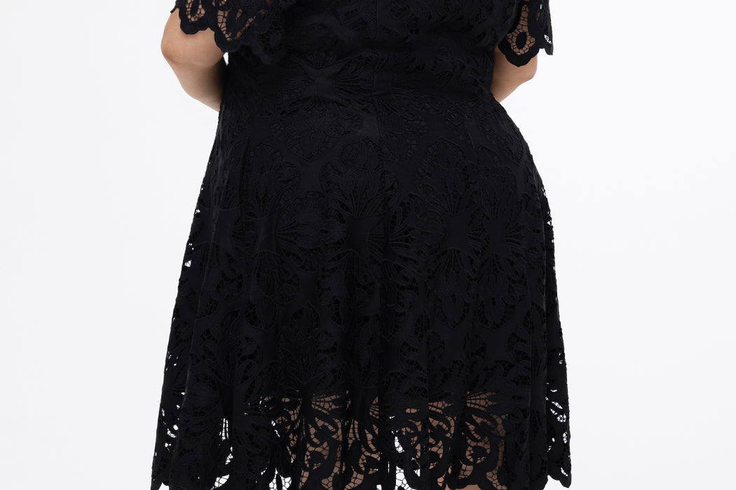 Plus size little black dress made of Guipure lace. Cap sleeves, scoop neckline and center back zipper. CE2601 available in sizes 14-24 in black. Celebrations by Sydney's Closet.