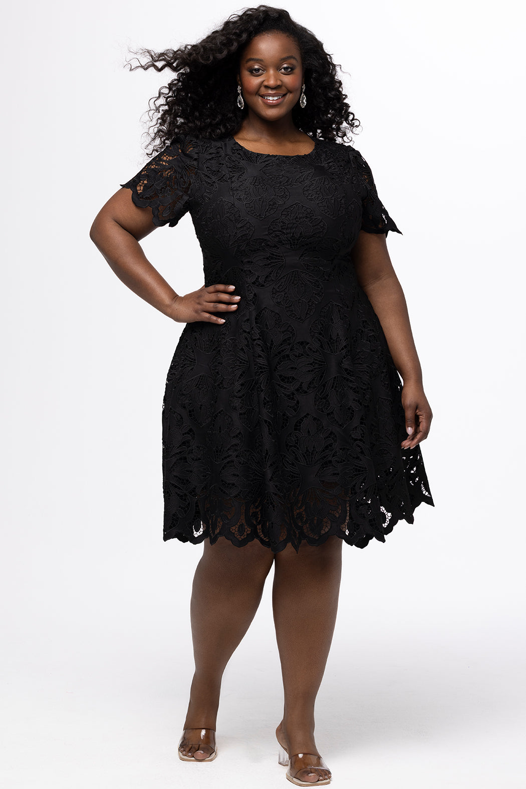 Plus size little black dress made of Guipure lace. Short sleeves, scoop neckline and center back zipper. CE2601 available in sizes 14-24 in black. Celebrations by Sydney's Closet.