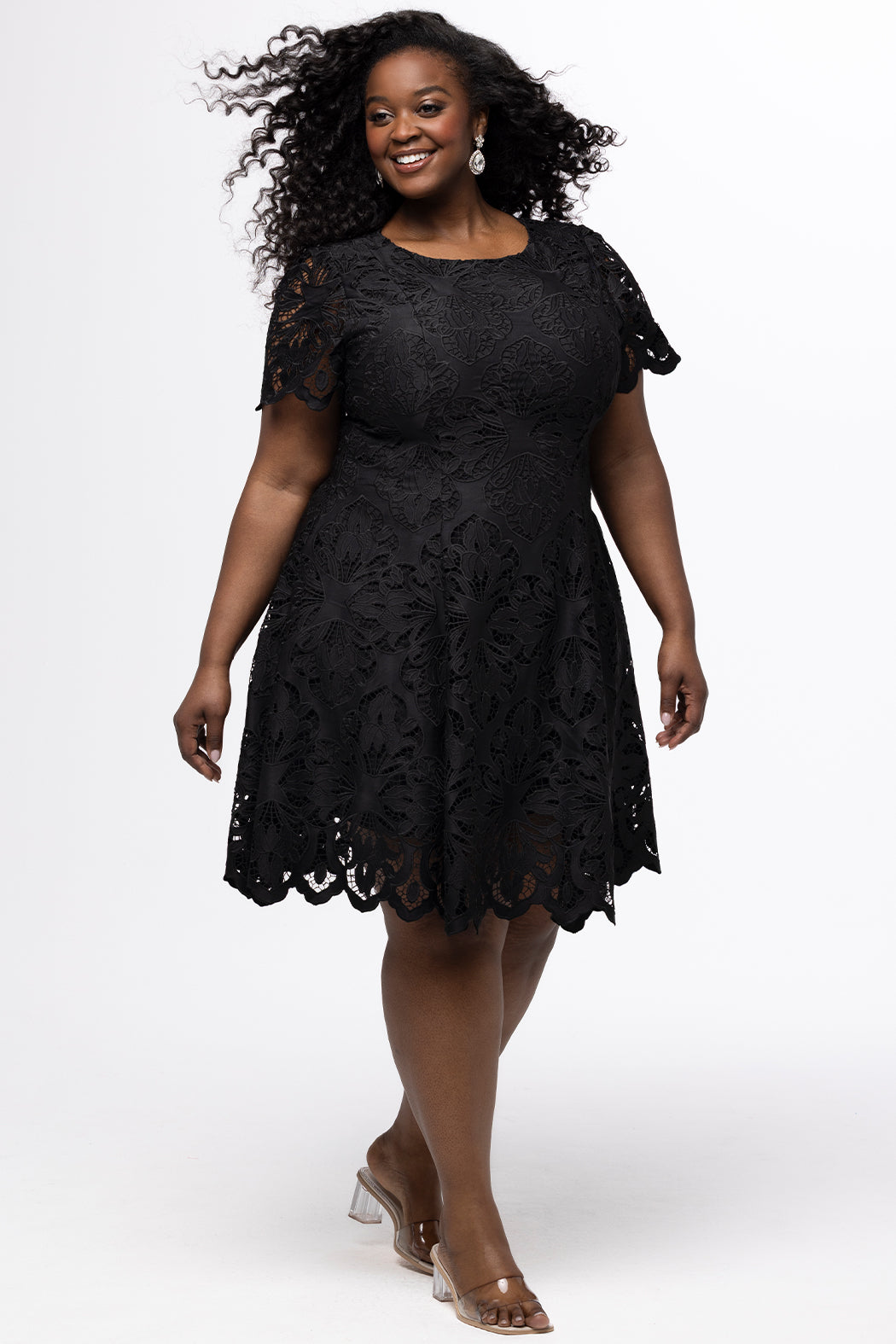 Plus size little black dress made of Guipure lace. Short sleeves, scoop neckline and center back zipper. CE2601 available in sizes 14-24 in black. Celebrations by Sydney's Closet.