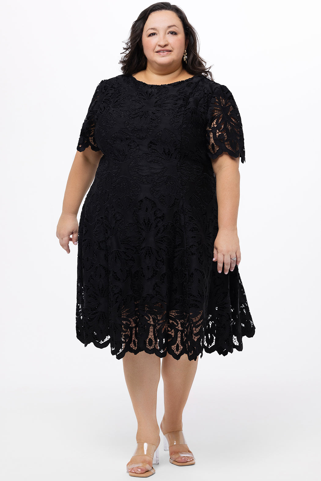 Plus size little black dress made of Guipure lace. Short sleeves, scoop neckline and center back zipper. CE2601 available in sizes 14-24 in black. Celebrations by Sydney's Closet.