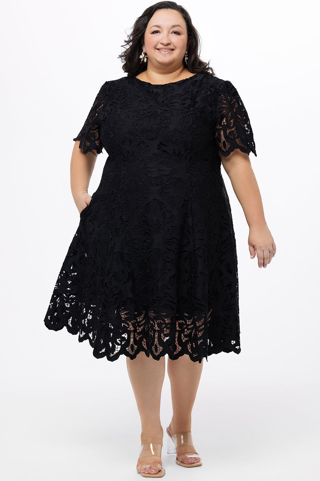 Plus size little black dress made of Guipure lace. Short sleeves, scoop neckline and center back zipper. CE2601 available in sizes 14-24 in black. Celebrations by Sydney's Closet.