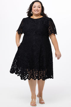 Plus size little black dress made of Guipure lace. Short sleeves, scoop neckline and center back zipper. CE2601 available in sizes 14-24 in black. Celebrations by Sydney's Closet.