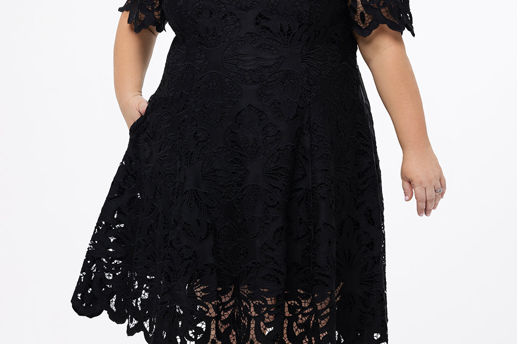 Plus size little black dress made of Guipure lace. Cap sleeves, scoop neckline and center back zipper. CE2601 available in sizes 14-24 in black. Celebrations by Sydney's Closet.