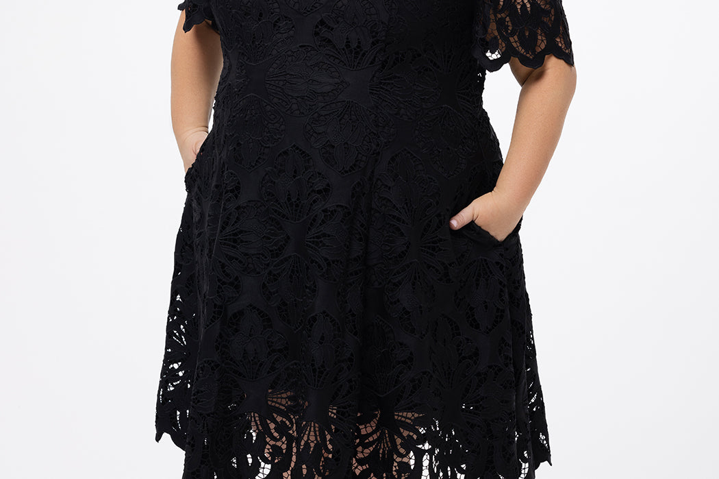 Plus size little black dress made of Guipure lace. Cap sleeves, scoop neckline and center back zipper. CE2601 available in sizes 14-24 in black. Celebrations by Sydney's Closet.