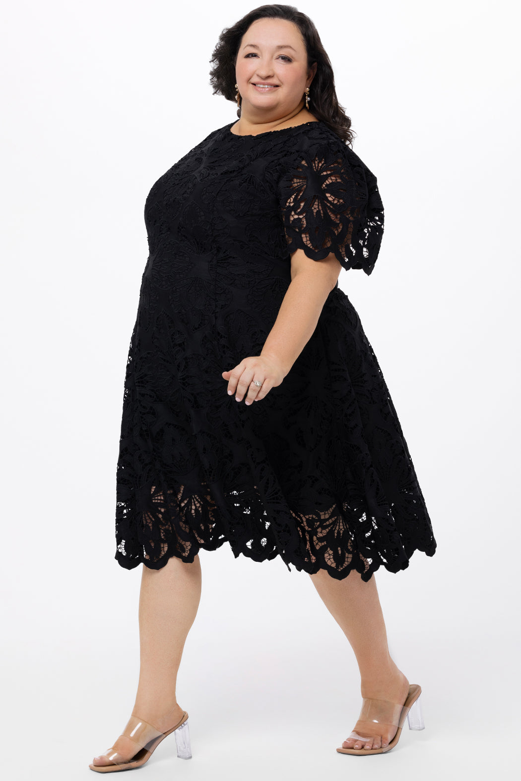 Plus size little black dress made of Guipure lace. Short sleeves, scoop neckline and center back zipper. CE2601 available in sizes 14-24 in black. Celebrations by Sydney's Closet.
