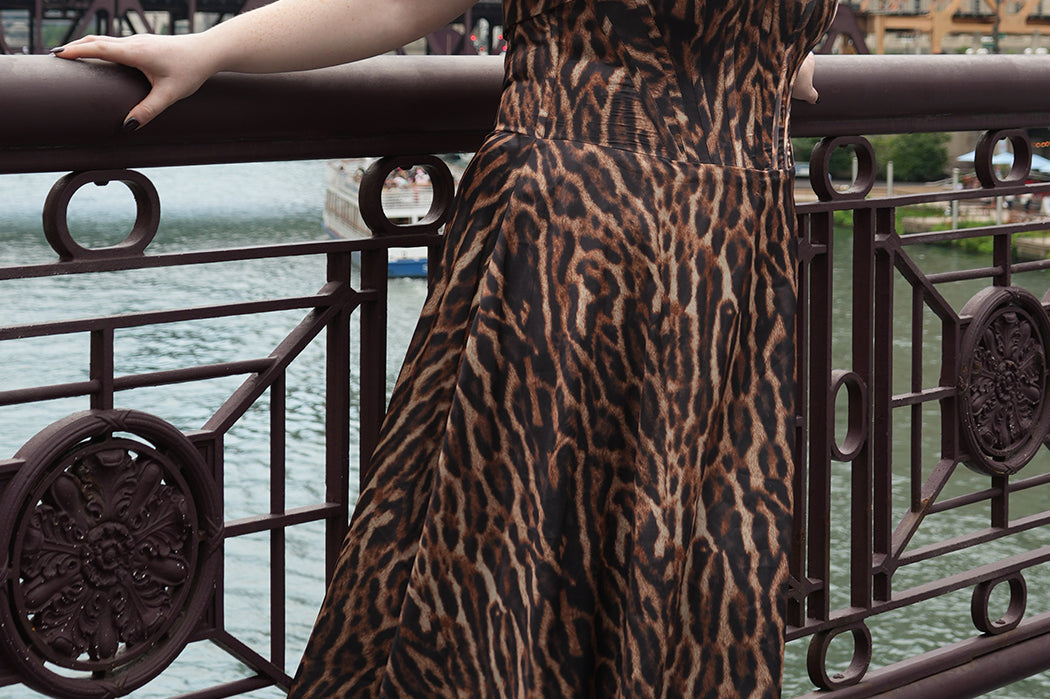 Plus size Tee length animal print dress.  fold over cuff detail, exposed corset boning, natural waistline, and A-line skirt with pockets and center back zipper. CE2603 available in sizes 14-24 in animal print. Celebrations by Sydney's Closet.