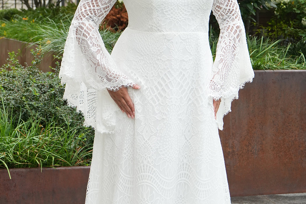 Boho crochet lace plus size wedding dress with V-neckline, illusion lace straps, illusion long flowy bell sleeves, natural wiasltine and slim A-line skirt finished with scalloped eyelash hem.  Available in ivory. Celebrations by Sydney's Closet style CE2604