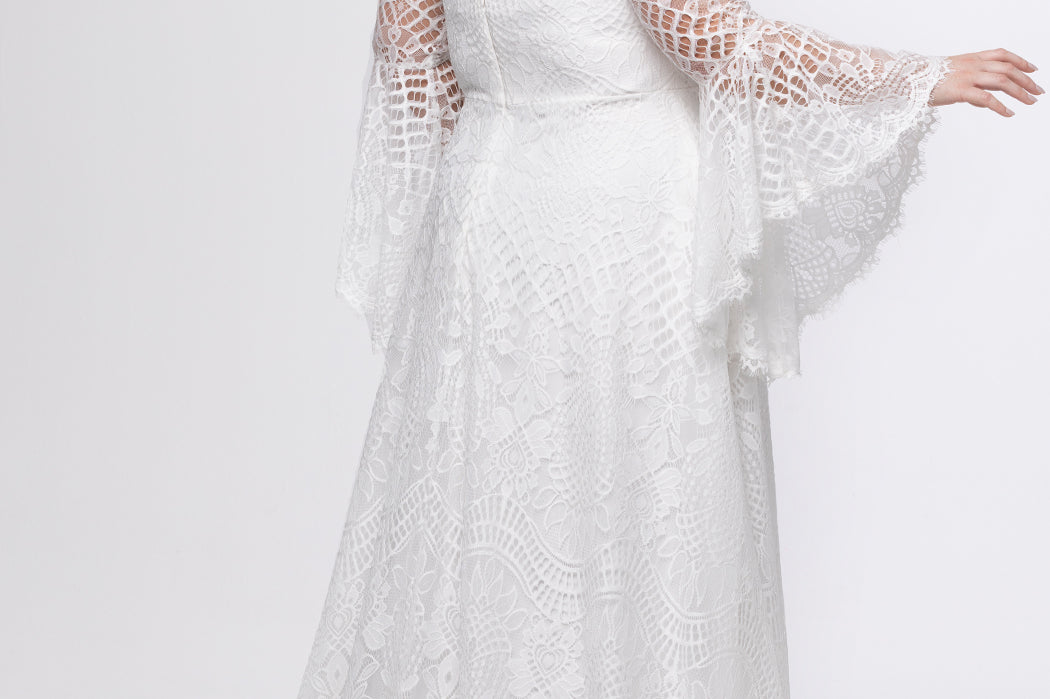 Boho crochet lace plus size wedding dress with V-neckline, illusion lace straps, illusion long flowy bell sleeves, natural wiasltine and slim A-line skirt finished with scalloped eyelash hem.  Available in ivory. Celebrations by Sydney's Closet style CE2604