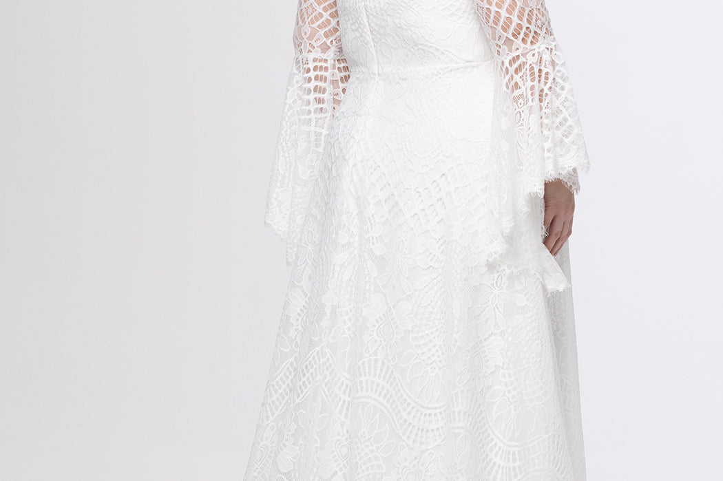 Boho crochet lace plus size wedding dress with V-neckline, illusion lace straps, illusion long flowy bell sleeves, natural wiasltine and slim A-line skirt finished with scalloped eyelash hem.  Available in ivory. Celebrations by Sydney's Closet style CE2604