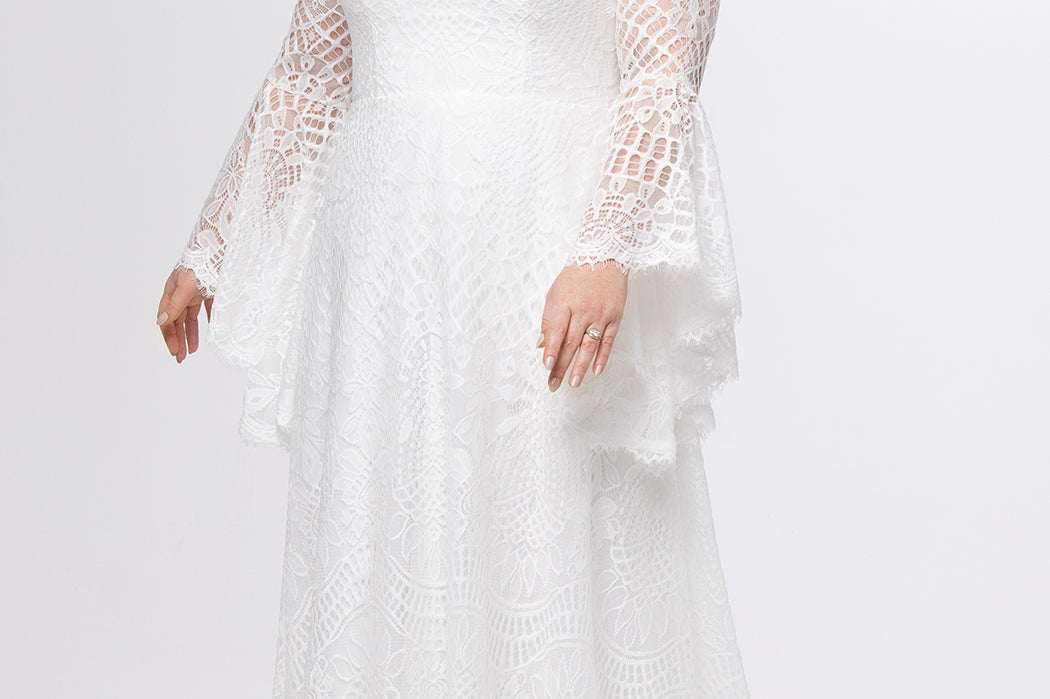 Boho crochet lace plus size wedding dress with V-neckline, illusion lace straps, illusion long flowy bell sleeves, natural wiasltine and slim A-line skirt finished with scalloped eyelash hem.  Available in ivory. Celebrations by Sydney's Closet style CE2604