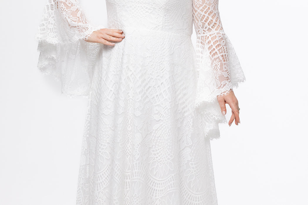 Boho crochet lace plus size wedding dress with V-neckline, illusion lace straps, illusion long flowy bell sleeves, natural wiasltine and slim A-line skirt finished with scalloped eyelash hem.  Available in ivory. Celebrations by Sydney's Closet style CE2604
