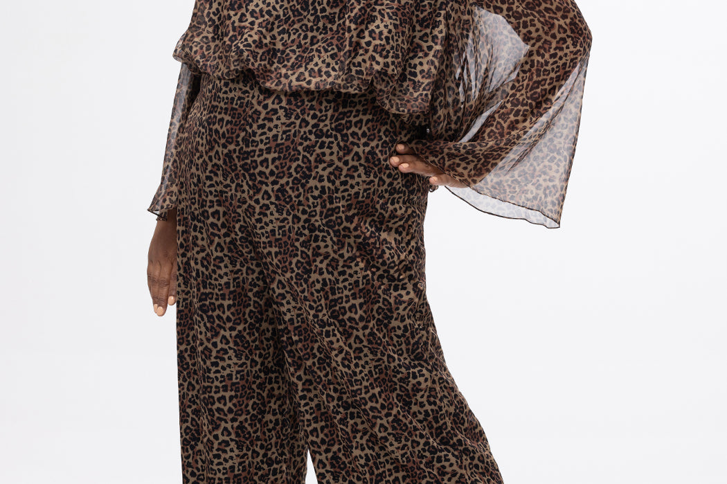 Plus size one-piece animal print jumpsuit. Long flowy chiffon sleeves and blouson bodice, elastic waist, and wide-leg pants. Center back zipper and scoop neckline. CE2607 available in sizes 14-28 in animal print. Celebration's by Sydney's Closet. 