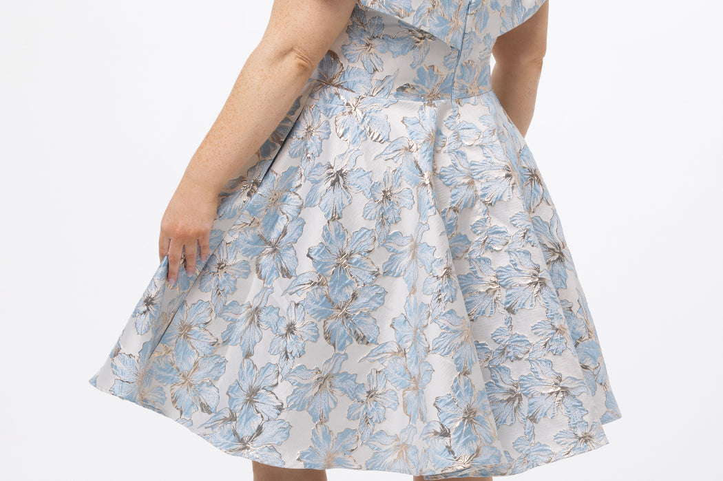 Celebrations by Sydney's Closet CE2610 in Light Blue Floral. 

Plus size knee-length party dress in metallic light blue floral brocde print. Off-the-shoulder neckline, natural waistline and A-line skirt with pockets. 