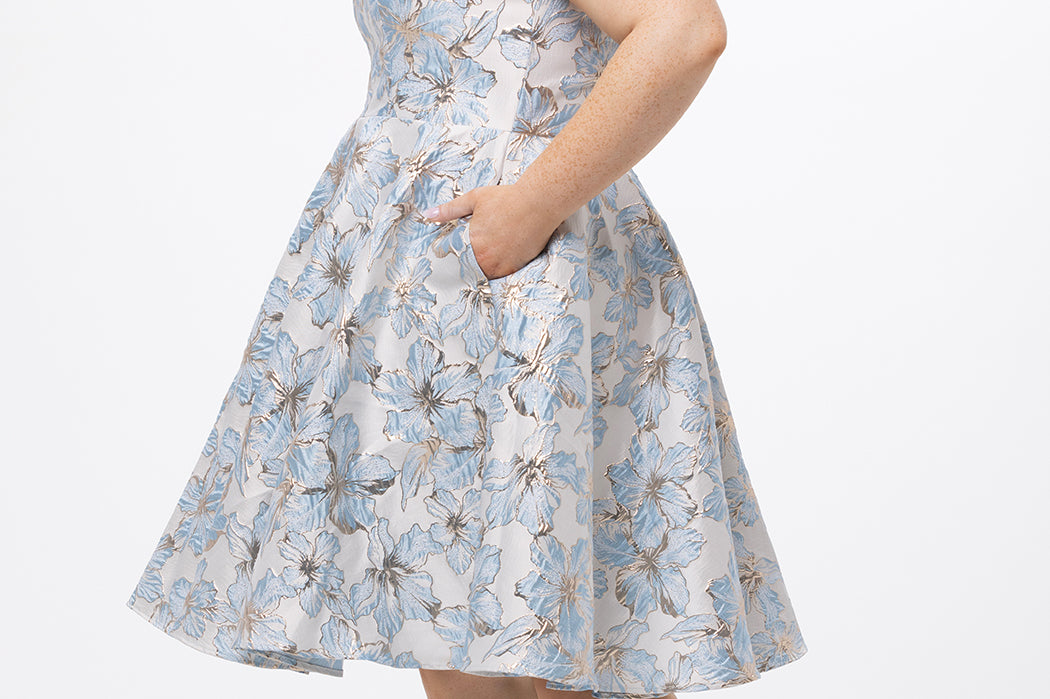Celebrations by Sydney's Closet CE2610 in Light Blue Floral. 

Plus size knee-length party dress in metallic light blue floral brocde print. Off-the-shoulder neckline, natural waistline and A-line skirt with pockets. 