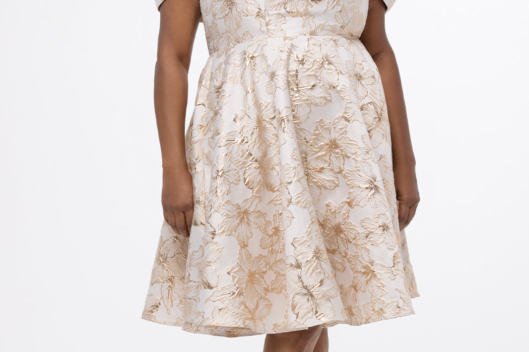 Celebrations by Sydney's Closet CE2610 in Gold Floral. 

Plus size knee-length party dress in metallic gold floral brocde print. Off-the-shoulder neckline, natural waistline and A-line skirt with pockets. 