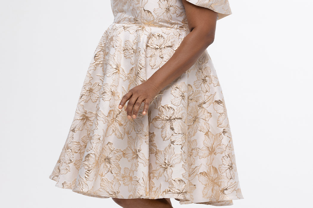 Celebrations by Sydney's Closet CE2610 in Gold Floral. 

Plus size knee-length party dress in metallic gold floral brocde print. Off-the-shoulder neckline, natural waistline and A-line skirt with pockets. 