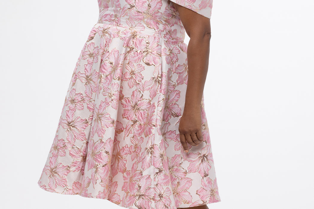 Celebrations by Sydney's Closet CE2610 in Light Pink Floral. 

Plus size knee-length party dress in metallic light pink floral brocde print. Off-the-shoulder neckline, natural waistline and A-line skirt with pockets. 