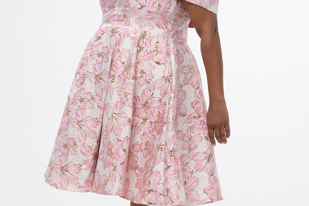 Celebrations by Sydney's Closet CE2610 in Light Pink Floral. 

Plus size knee-length party dress in metallic light pink floral brocde print. Off-the-shoulder neckline, natural waistline and A-line skirt with pockets. 