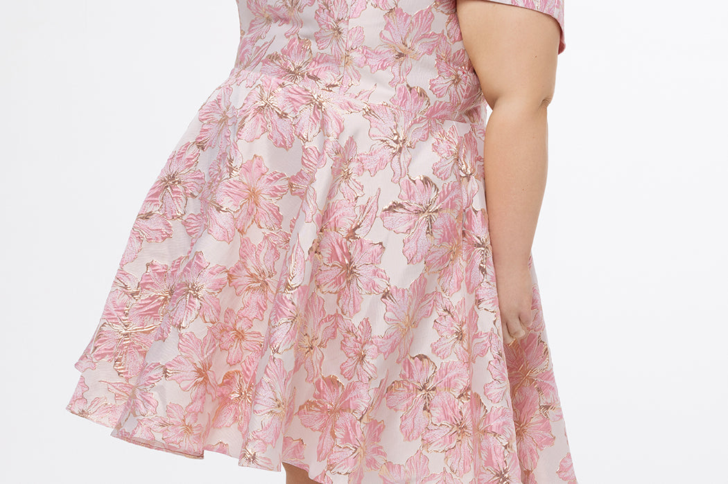 Celebrations by Sydney's Closet CE2610 in Light Pink Floral. 

Plus size knee-length party dress in metallic light pink floral brocde print. Off-the-shoulder neckline, natural waistline and A-line skirt with pockets. 