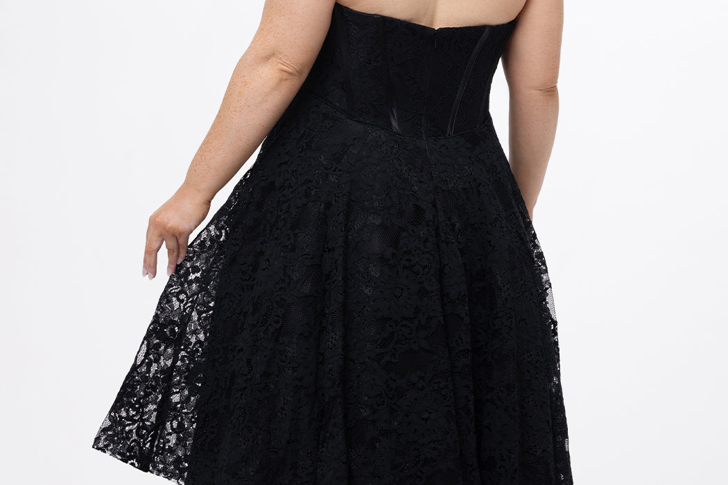 Celebrations by Sydney's Closet Style CE2613 in black. 

Plus size strapless black tea-length dress with sweetheart neckline, exposed corset boning on bustier bodice and tea-length skirt in all over stretch lace. 