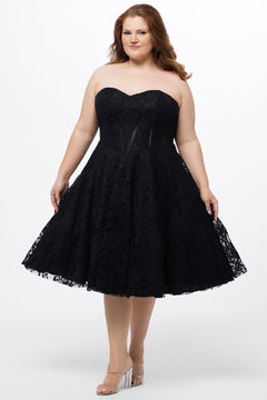 Celebrations by Sydney's Closet Style CE2613 in black. 

Plus size strapless black tea-length dress with sweetheart neckline, exposed corset boning on bustier bodice and tea-length skirt in all over stretch lace. 