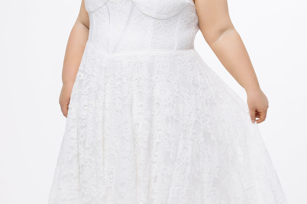 Celebrations by Sydney's Closet Style CE2613 in white. 

Plus size strapless white tea-length dress with sweetheart neckline, exposed corset boning on bustier bodice and tea-length skirt in all over stretch lace. 